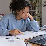 Une lycéenne compare son raisonnement dans un cahier avec une aide sur ordinateur
